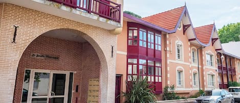 A building with a brick facade, a large arched entrance, and a balcony with red railings.