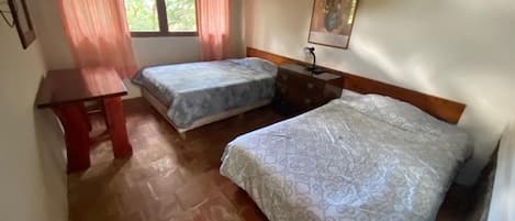 Una habitación con dos camas, un escritorio y una ventana con cortinas.