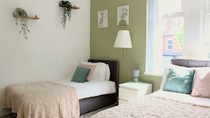 A bedroom with two beds, a nightstand, a lamp, and wall-mounted plants. - 3-Bed Bearwood | Midland Met, No CAZ, Free Parking (Smethwick)