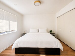 A bedroom with a bed, bedside tables, a potted plant, and a wardrobe. - Cozy & Quiet 4 bed/ 2bath l 4 KING beds Family & Group Friendly l Spacious (Tempe)