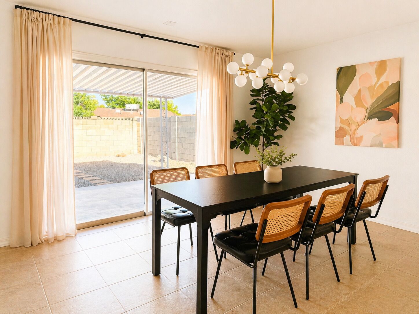 A dining area with a table, chairs, a potted plant, and a ceiling light fixture.