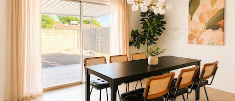 A dining area with a table, chairs, a potted plant, and a ceiling light fixture.