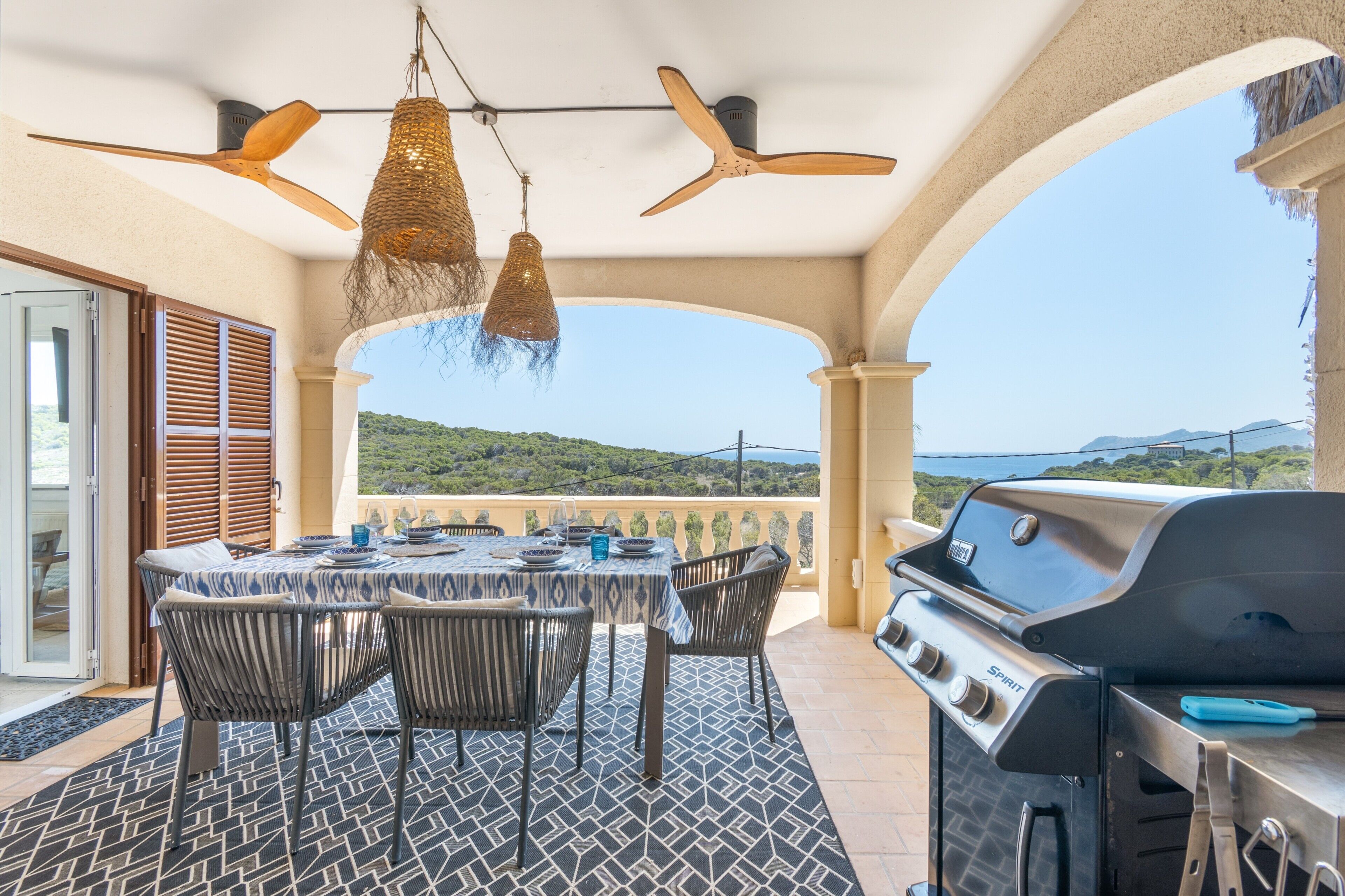 Un patio exterior con mesa, sillas, una parrilla y vistas del paisaje.