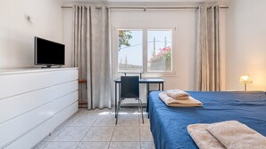 A hotel room with a bed, a desk, a chair, a television, and a window with curtains.