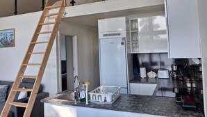 Una cocina moderna con refrigerador integrado, una escalera de madera y un comedor con sofá.