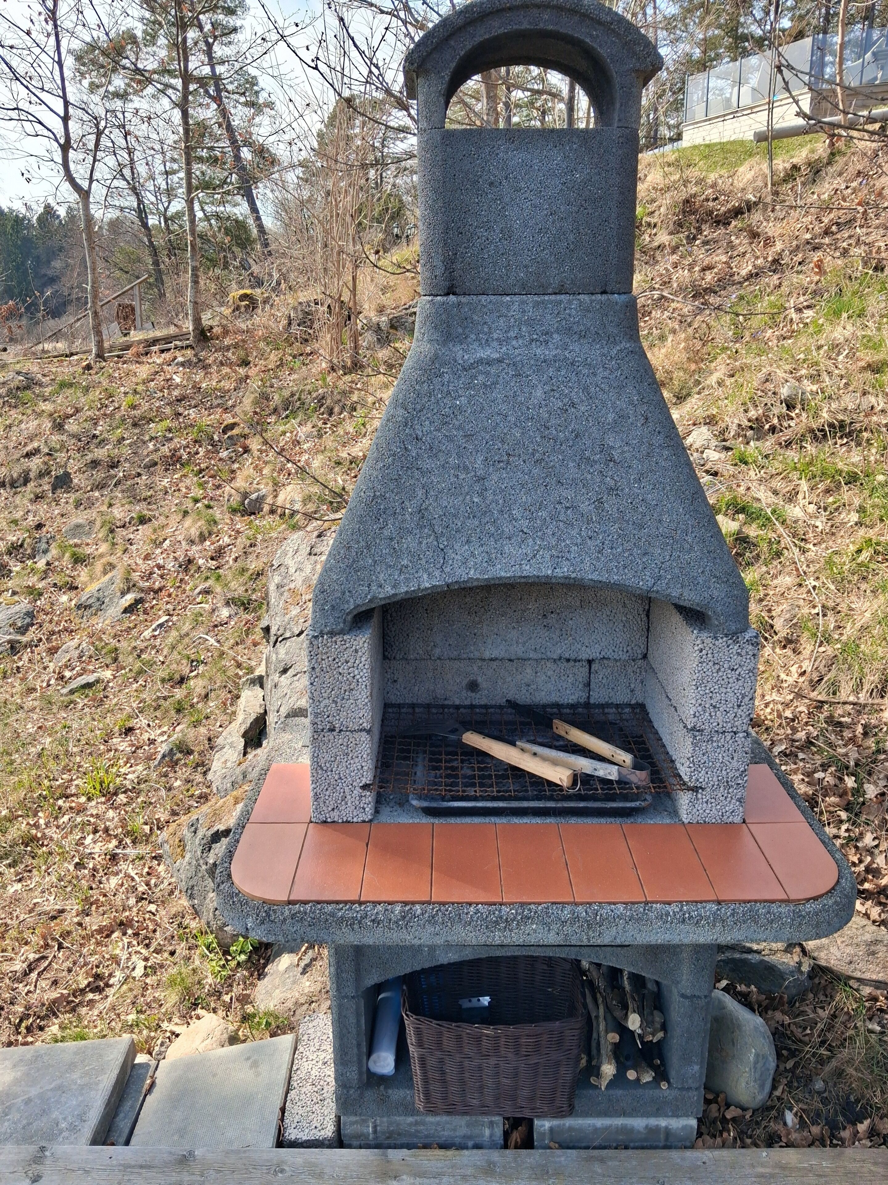A stone-built outdoor oven with a brick base, surrounded by natural landscape.