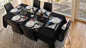 Comedor con una mesa dispuesta para seis personas, ventanas amplias y vista a un lago.