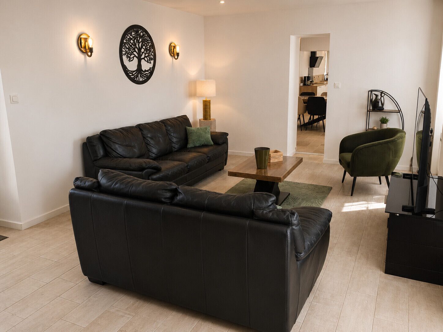 Un salon moderne avec un canapé en cuir noir, une petite table basse en bois et un fauteuil vert.
