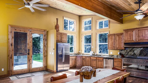 Una cocina con gabinetes de madera, un refrigerador de acero inoxidable, una estufa y ventanas amplias.