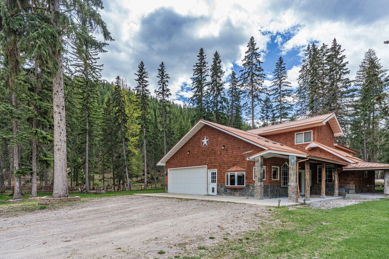 A two-story house with a garage, surrounded by a forest.