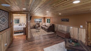 Interior de una cabaña de troncos con cama, sofá y un letrero que indica que el lugar está a 3 kilómetros del Lago Avalanche.