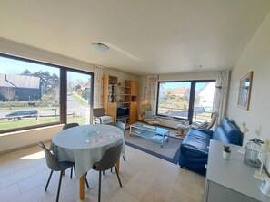 Ein großzügiger Wohnbereich mit Esstisch, Sofa und Fernseher.