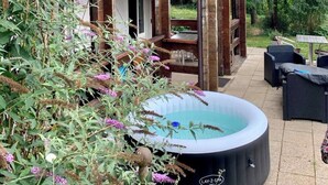 A wooden house with a balcony, a hot tub, and outdoor furniture.