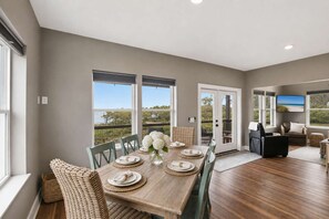Un comedor con una mesa preparada para cuatro, una silla de mimbre y vistas al exterior.