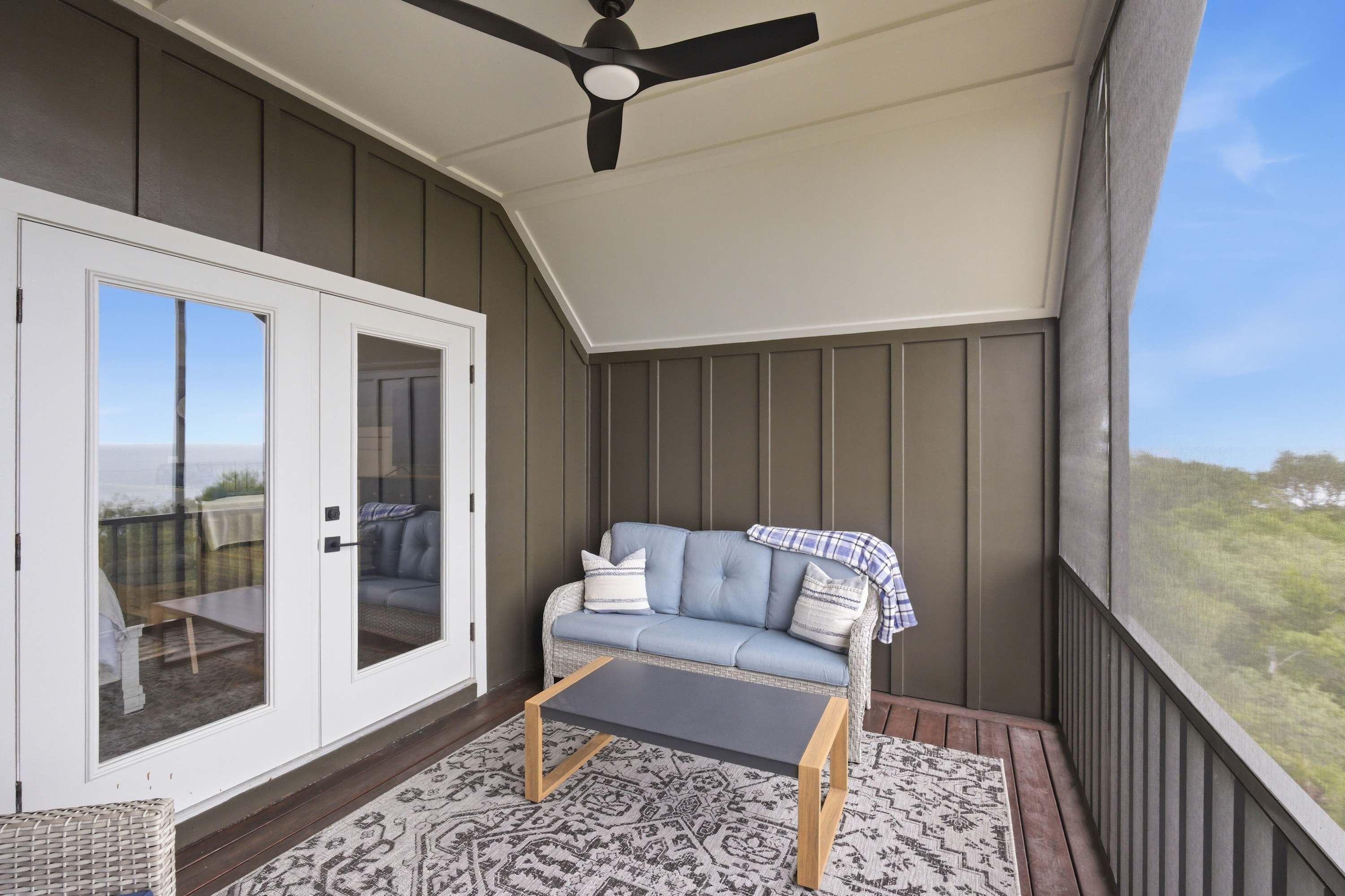 Un balcon avec un canapé, une table et un ventilateur de plafond.