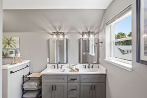 Un baño con dos lavamanos, una ventana y un espejo.