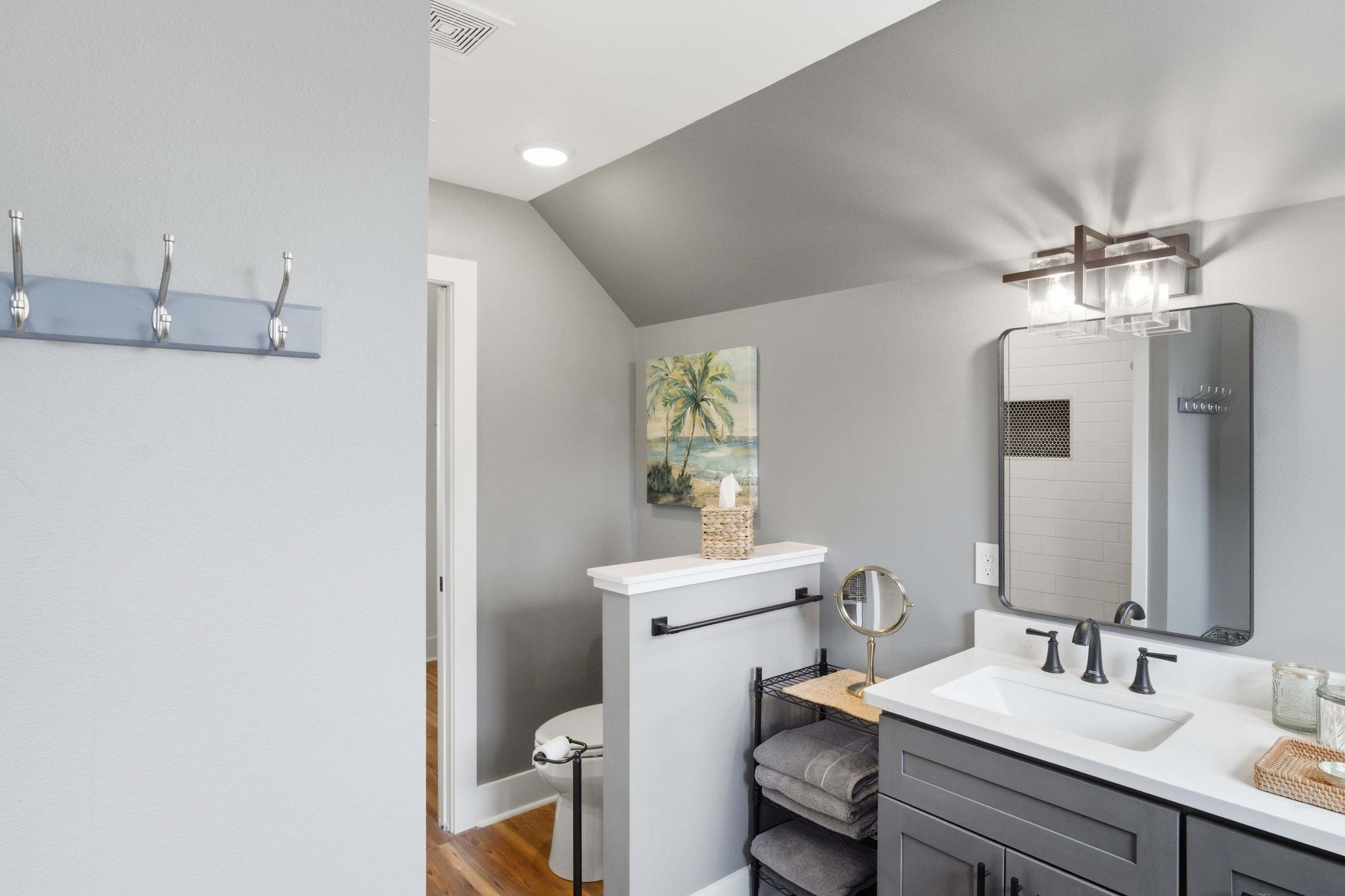 A modern bathroom with a white sink, a large mirror, and a towel rack.