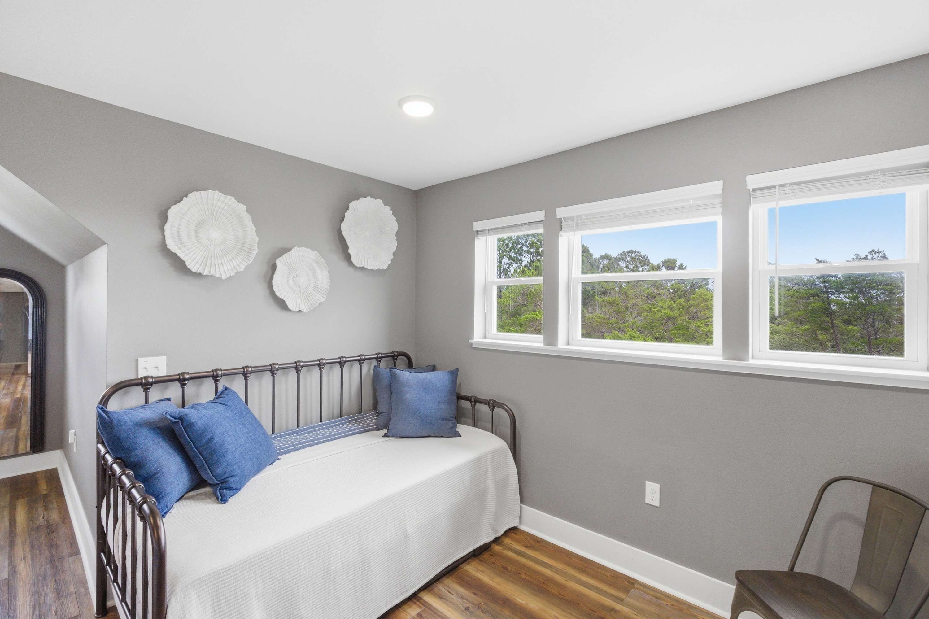 Une chambre à coucher avec un lit, une chaise et une fenêtre donnant sur des arbres.