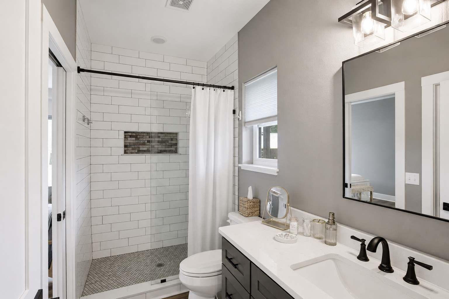 A modern bathroom with a shower, toilet, and vanity with a mirror.