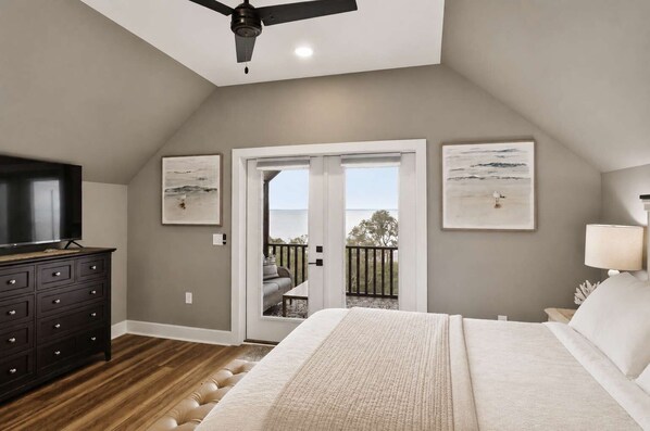 A bedroom with a bed, a dresser, a ceiling fan, and a balcony with a view. - New- Seabreeze-Bay Front -Pet Friendly (Eastpoint)