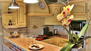 A kitchen with a clock, a sink, a stove, and a plant.