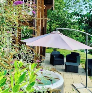 Un espace extérieur aménagé avec une table et des chaises, un élément décoratif aquatique et une structure en bois agrémentée de plantes.
