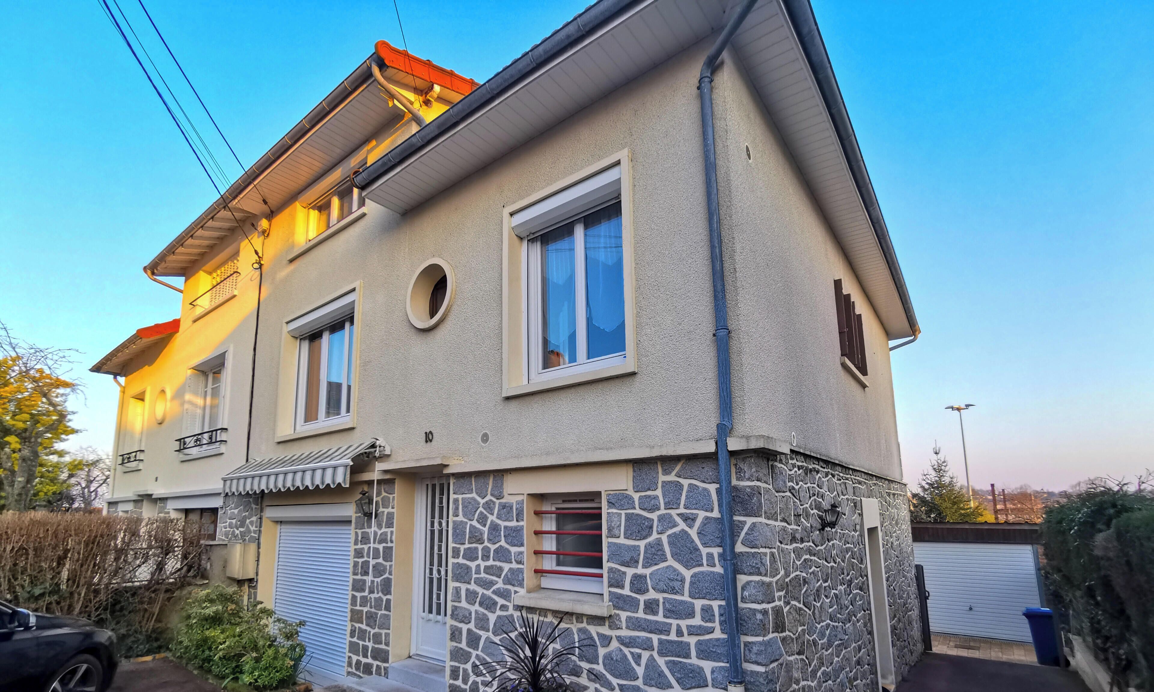 Une maison à deux étages avec une façade en pierre, un garage et le numéro « 10 » bien visible sur le mur.