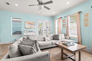 A living room with a sofa, coffee table, ceiling fan, and artwork on the walls. - Mins from Beach • Sleeps 17 • Outdoor Seating (Destin)