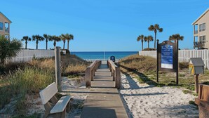 A beach pathway leading to the ocean, flanked by palm trees and a safety sign. - Mins from Beach • Sleeps 17 • Outdoor Seating (Destin)