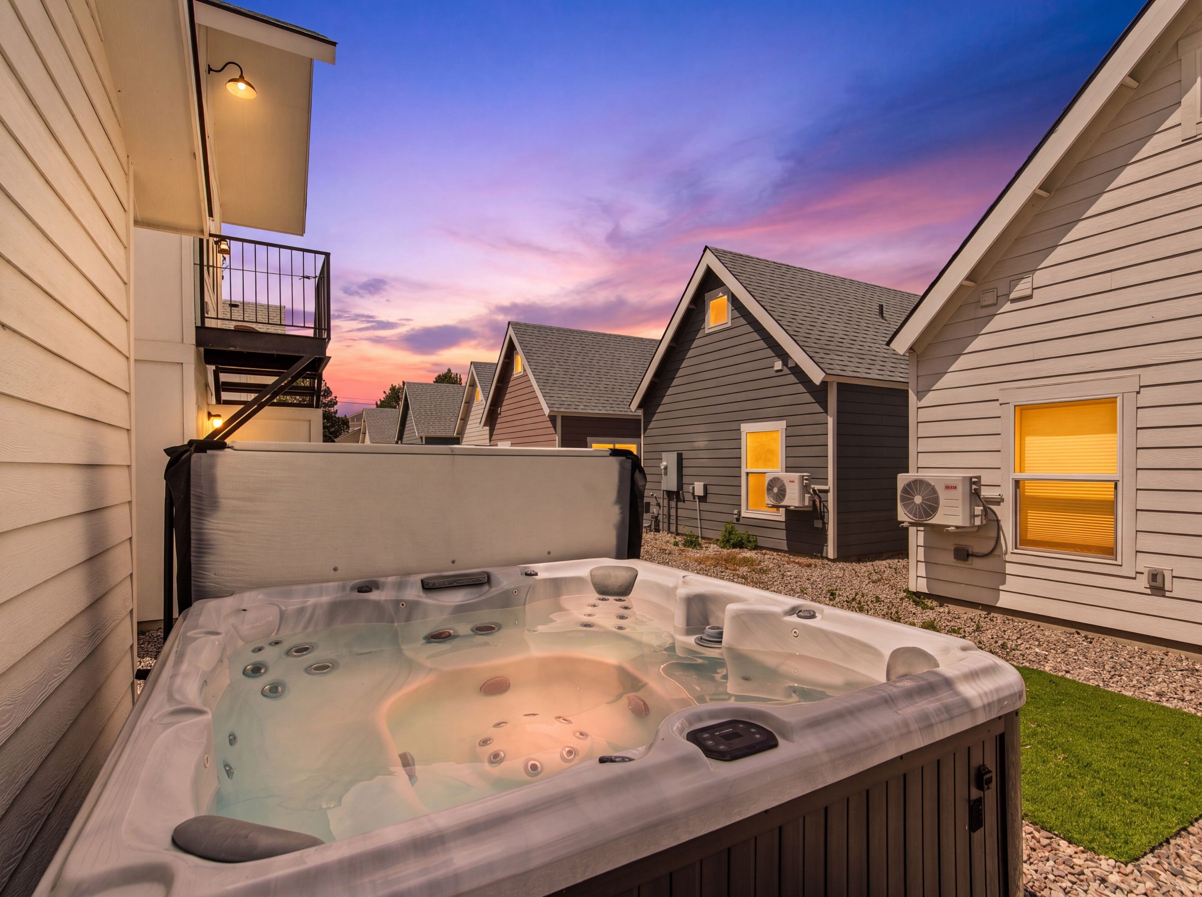 Un jacuzzi dans un jardin, avec une maison en arrière-plan.