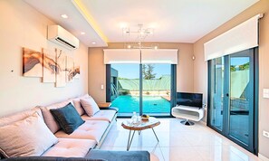 Ein modernes Wohnzimmer mit Sofa, Fernseher, Pool und Balkon.