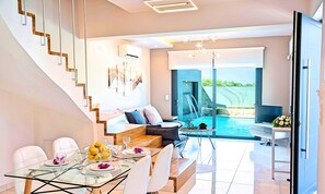 Ein modernes Interieur mit Essbereich, einer Couch, einem Pool und einer Treppe.
