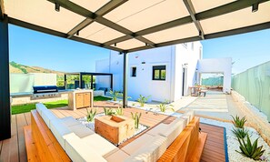 Eine moderne Außenpatio mit Holzterrasse, einer integrierten Sitzecke und einem Grill.