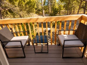 A wooden deck with two chairs and a small table, surrounded by a wooden railing.