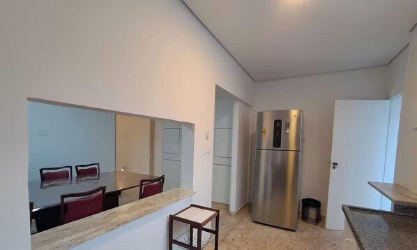Eine kompakte Küche mit Edelstahlkühlschrank, einem Esstisch mit Stühlen und einer kleinen Arbeitsfläche.
