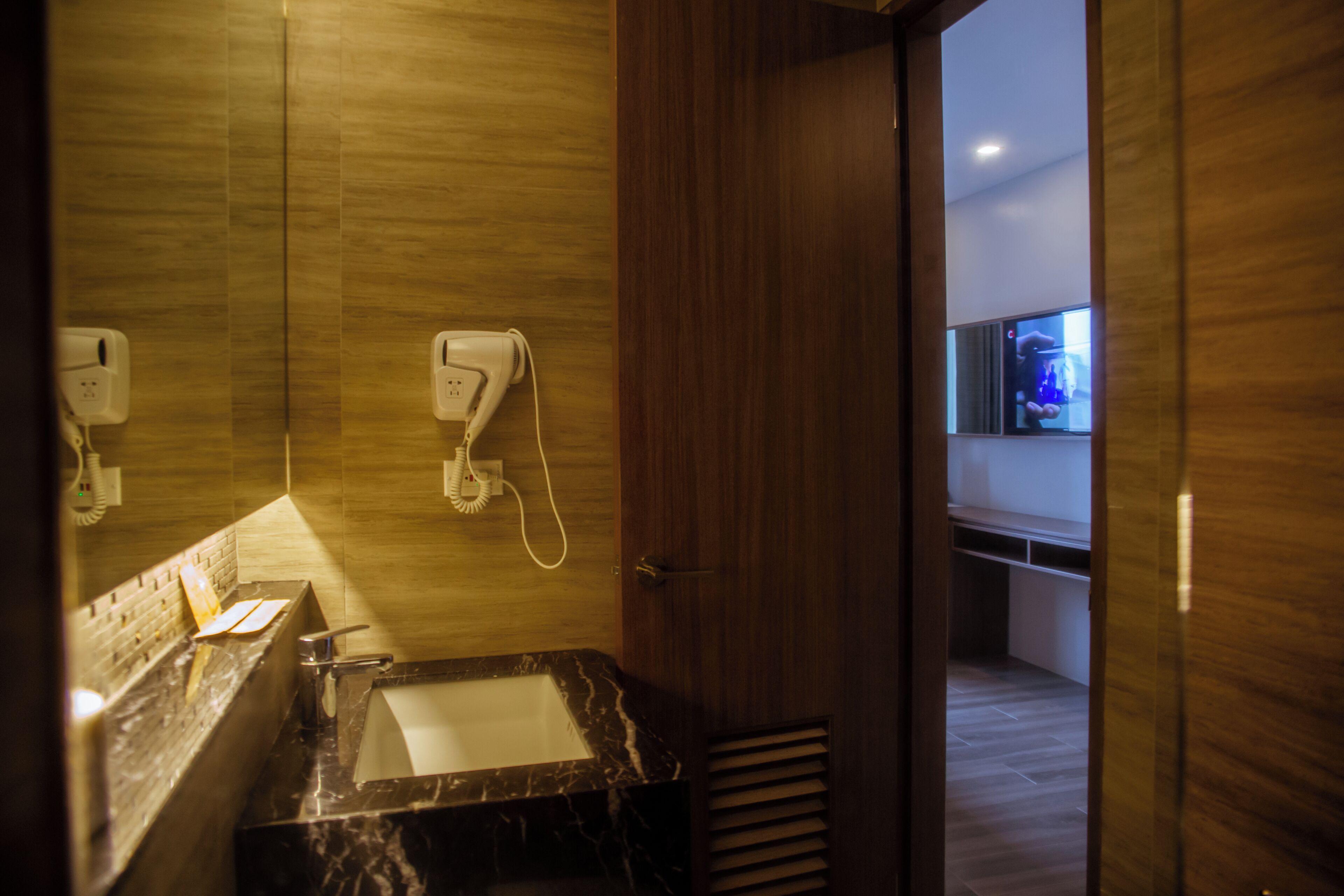Une salle de bain moderne avec un lavabo en marbre, un sèche-mains et un miroir.