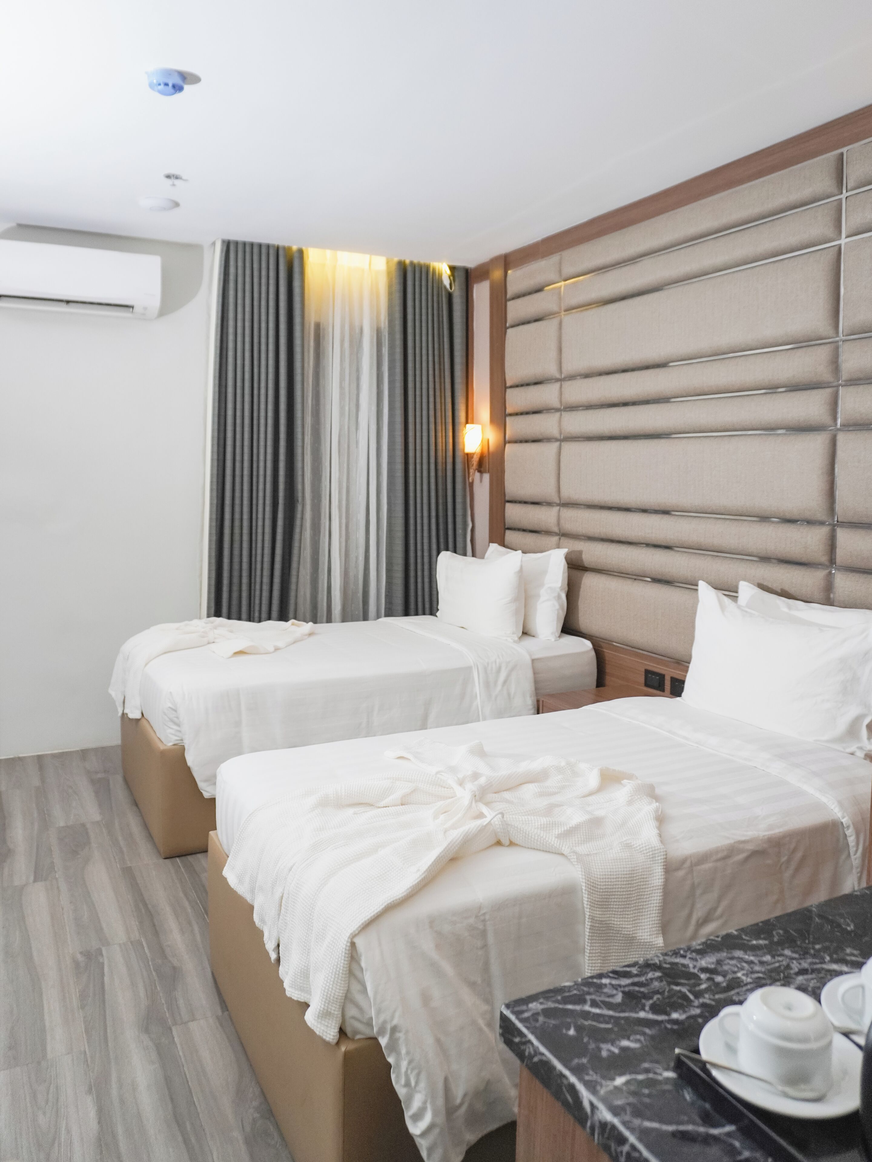 Une chambre d’hôtel avec deux lits, une table en marbre et un climatiseur fixé au mur.