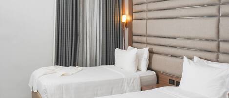 Une chambre d’hôtel avec deux lits, une table en marbre et un climatiseur fixé au mur.