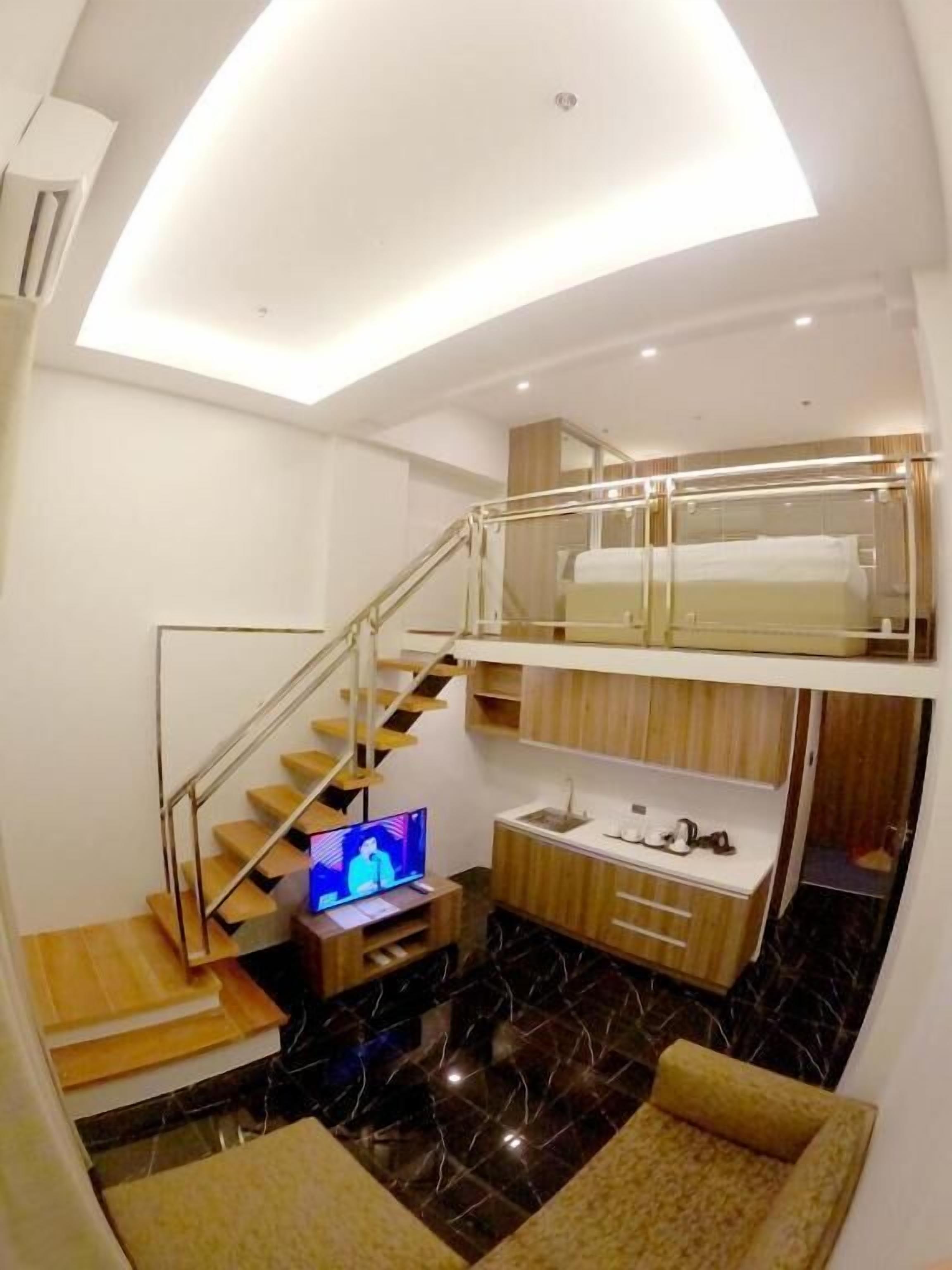 A compact living space with a mezzanine, a TV, a sink, and a staircase.