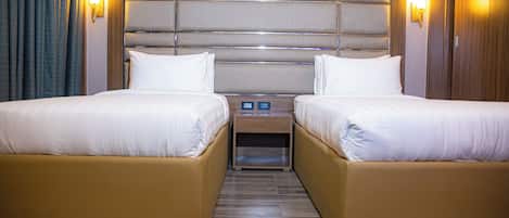 A hotel room with two beds, a wooden headboard, bedside lamps, and a nightstand.
