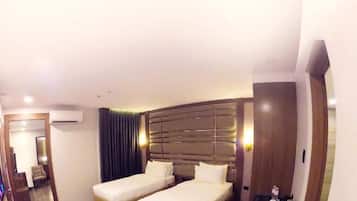 A hotel room with two beds, a desk, a chair, a mirror, and a small table with a decorative item.