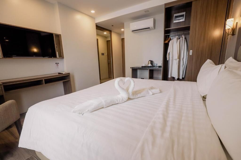 A hotel room with a bed, a TV, a desk, and a wardrobe.
