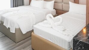 A hotel room with two beds, a wooden headboard, a marble bedside table, and a window with curtains. - El Vistra Hotel (Angeles City)