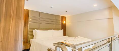 A modern hotel room with a bed, a wooden panel wall, a glass railing, and recessed ceiling lights.