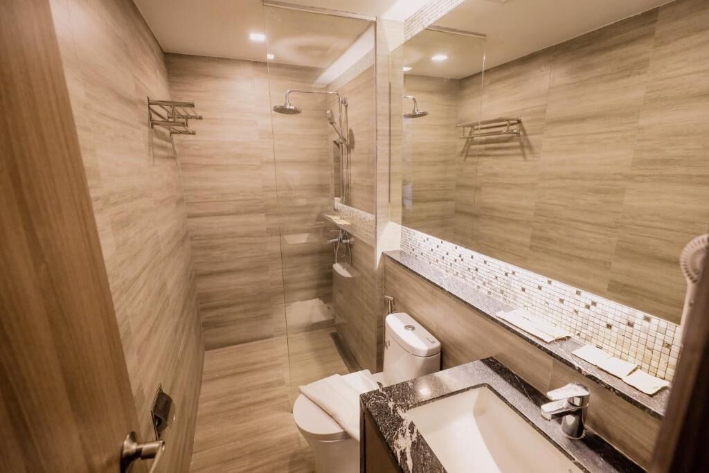 Un baño moderno con ducha de vidrio, inodoro y lavamanos con espejo.