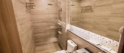 Un baño moderno con ducha de vidrio, inodoro y lavamanos con espejo.