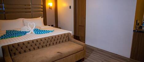 Una habitación de hotel con una cama, un sofá, una lámpara fijada en la pared y una puerta de madera.
