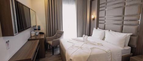 Une chambre d’hôtel équipée d’un lit, d’un bureau, d’une chaise, d’une télévision et d’une grande fenêtre avec des rideaux.