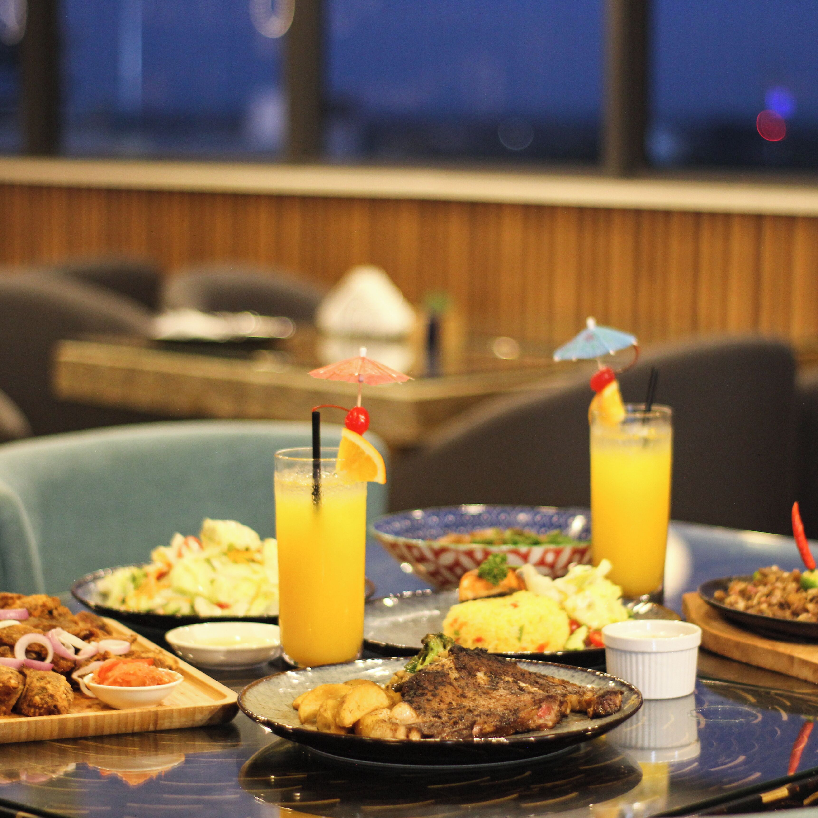 A dining table with various dishes, drinks, and a view of the room.