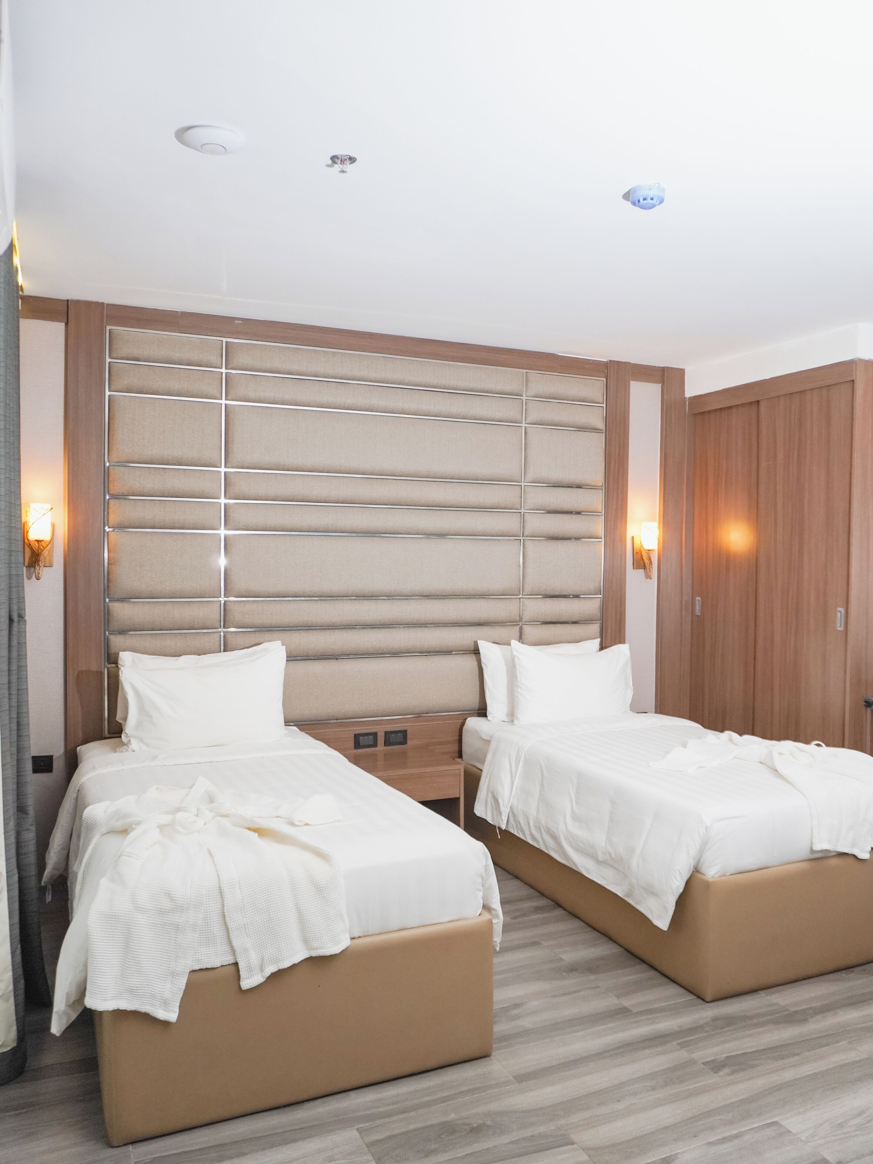 Ein Hotelzimmer mit zwei Betten, einem Holzkopfende, Nachttischlampen und einem Kleiderschrank.
